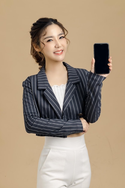 Glimlach mooie Aziatische zakenvrouw met mobiele telefoon op geïsoleerde beige achtergrond