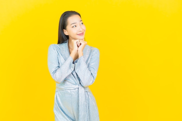 Glimlach van de portret de mooie jonge aziatische vrouw met actie op gele muur