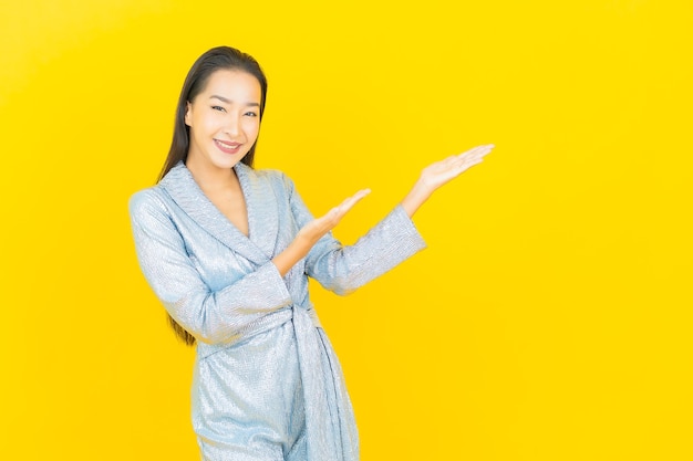 Glimlach van de portret de mooie jonge aziatische vrouw met actie op gele muur