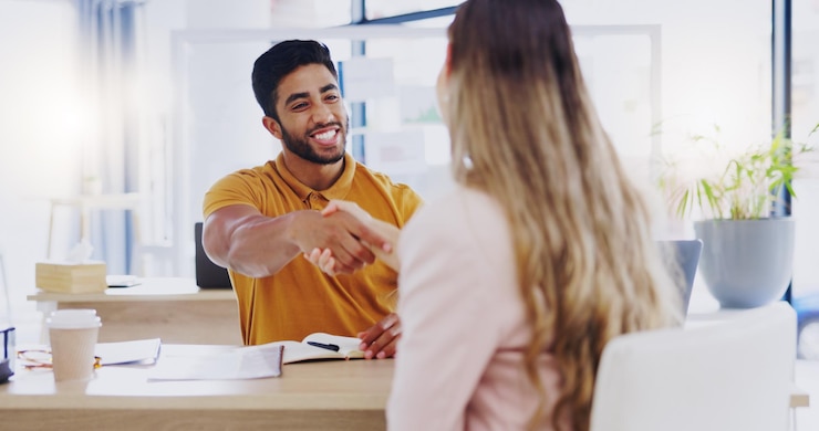 Foto glimlach zakenmensen en handdruk voor partnerschapsovereenkomst of introductie op de werkplek gelukkige man en vrouw schudden elkaar de hand voor overeenkomst b2b of onboarding gefeliciteerd of welkom bij bedrijf