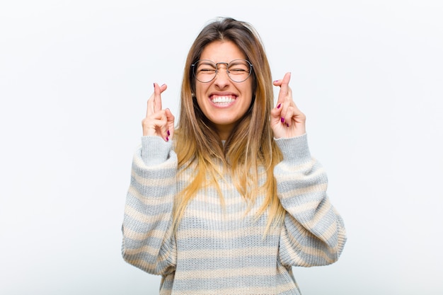 glimlachen en angstig beide vingers kruisen, zich zorgen maken en wensen of hopen op geluk