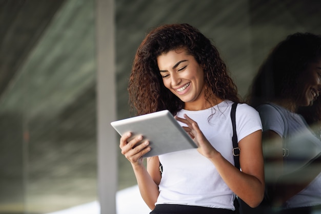 Glimlachend Arabisch meisje die digitale tablet op bedrijfsachtergrond gebruiken.