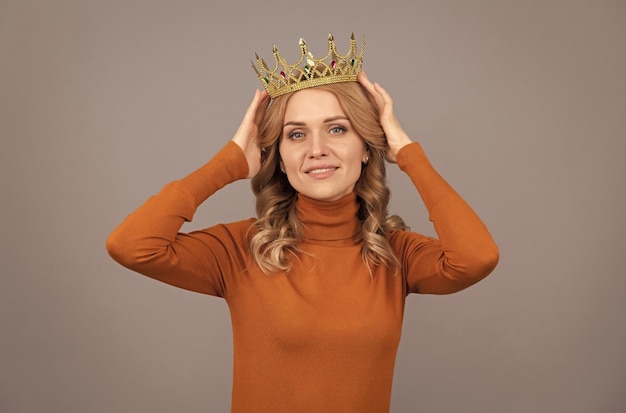 Foto glimlachend blond meisje met krullend haar draagt een kroon egoïsme