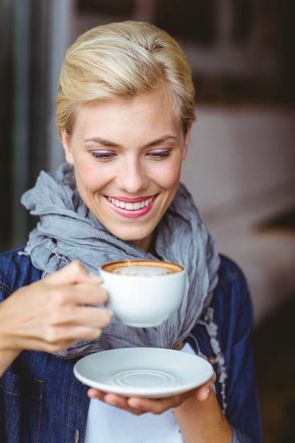 Foto glimlachend blonde die van een kop van cappuccino genieten