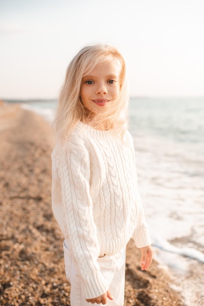 Glimlachend blonde jongen meisje permanent op zandstrand over zee