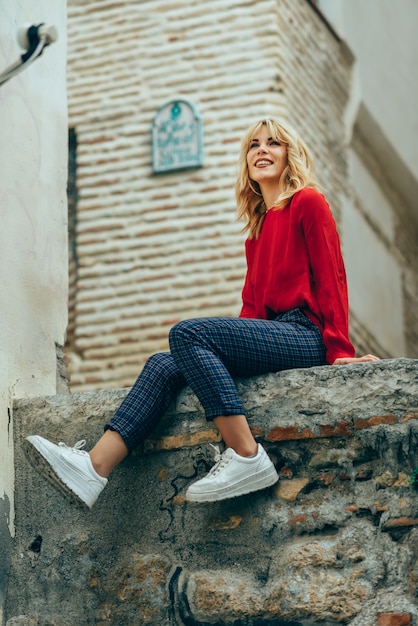 Glimlachend blondemeisje die met rood overhemd in openlucht van het leven genieten.