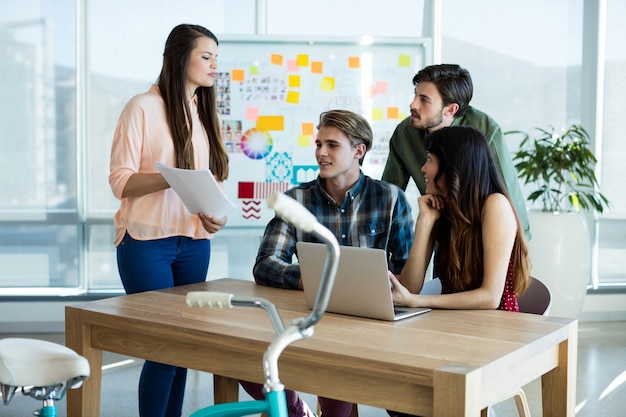 Glimlachend creatief commercieel team dat over laptop in bureau bespreekt