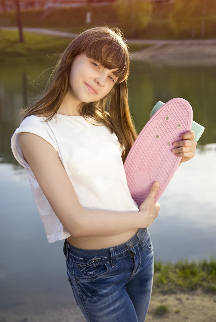 Foto glimlachend de holdingsskateboard van het tienermeisje dichtbij meer