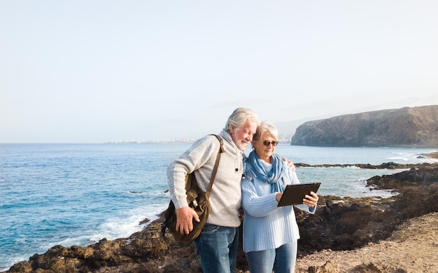 Foto glimlachend echtpaar met een digitale tablet aan zee tegen de lucht