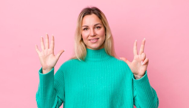 Foto glimlachend en vriendelijk kijkend met nummer acht of achtste met hand vooruit aftellend