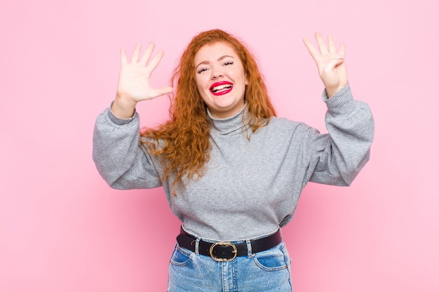 glimlachend en vriendelijk kijkend, met nummer negen of negende met de hand naar voren