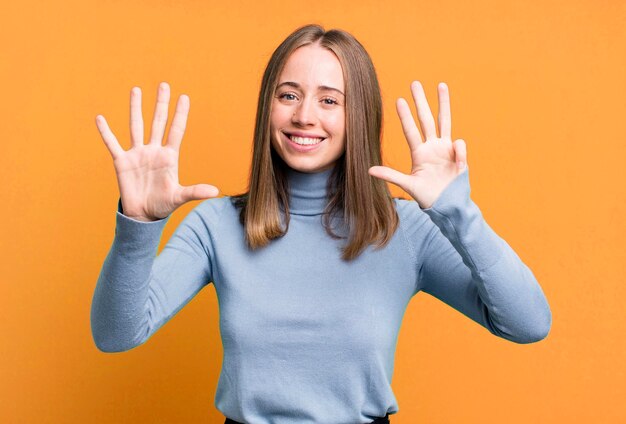 Glimlachend en vriendelijk kijkend met nummer negen of negende met hand vooruit aftellend