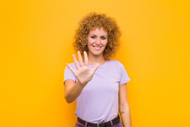 glimlachend en vriendelijk kijkend, met nummer vijf of vijfde met de hand naar voren, aftellend