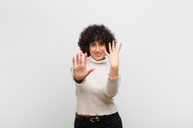 glimlachend en vriendelijk kijkend, nummer negen of negende tonend met hand naar voren, aftellend