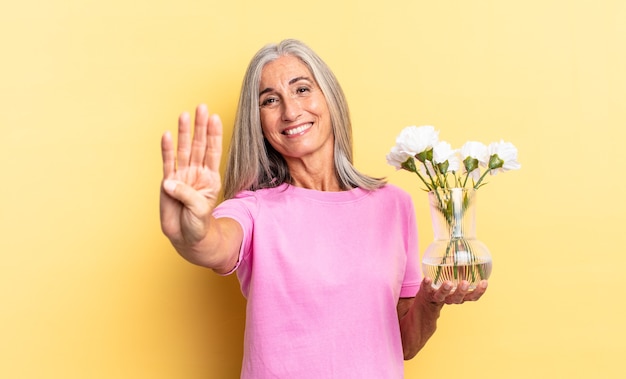 Glimlachend en vriendelijk kijkend, nummer vier of vierde tonend met hand naar voren, aftellend met decoratieve bloemen