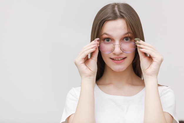 Foto glimlachend fronsend kantoor meisje camera staren door bril op witte achtergrond. jonge vrouw brillen aanpassen. bril met concept.