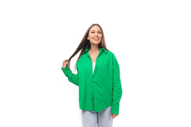 Glimlachend gelukkig jong Europees vrouwelijk model met goed verzorgd zwart haar en make-up gekleed in een groene