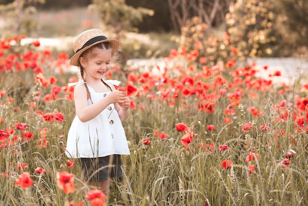 Glimlachend gelukkig kindmeisje met bloemstandaard in papaverweide