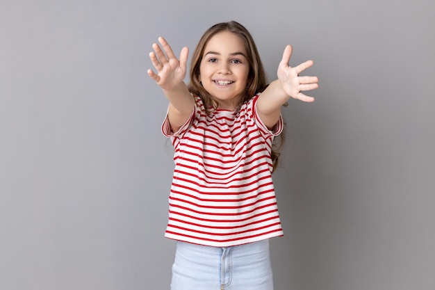 Glimlachend gelukkig meisje met gestreept T-shirt met uitgestrekte handen om gratis knuffels te omarmen