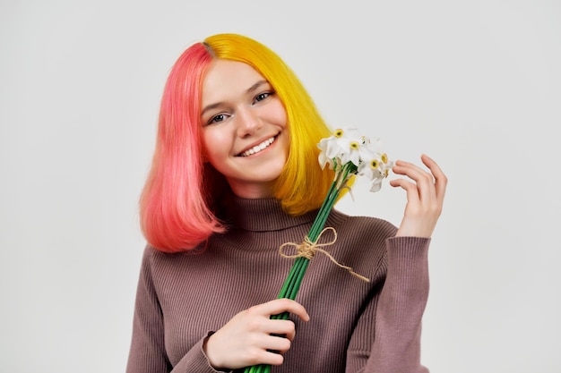 Glimlachend gelukkig trendy tienermeisje met boeket van witte narcissen bloemen op lichte achtergrond