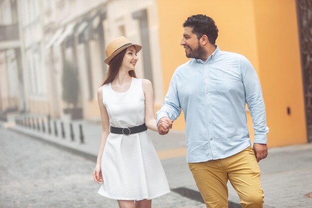 Glimlachend internationaal echtpaar loopt hand in hand in de stad