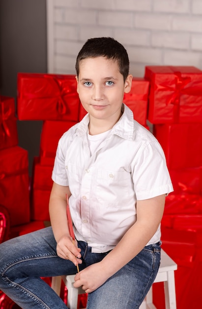 Glimlachend jong geitje zittend op een stoel met rode geschenkdozen erachter