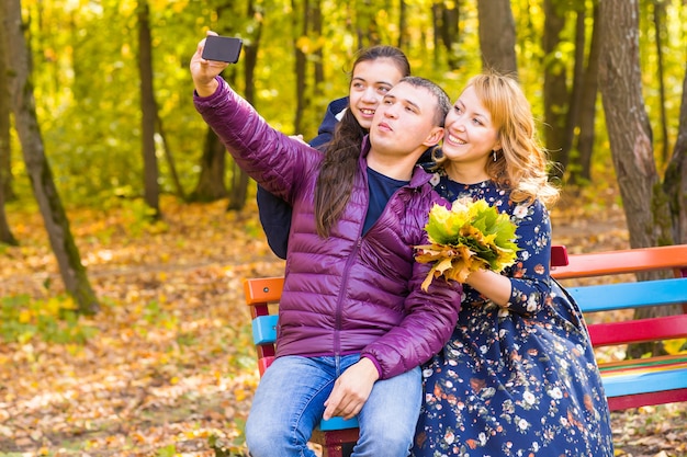 Glimlachend jong gezin selfies nemen op een herfstdag.