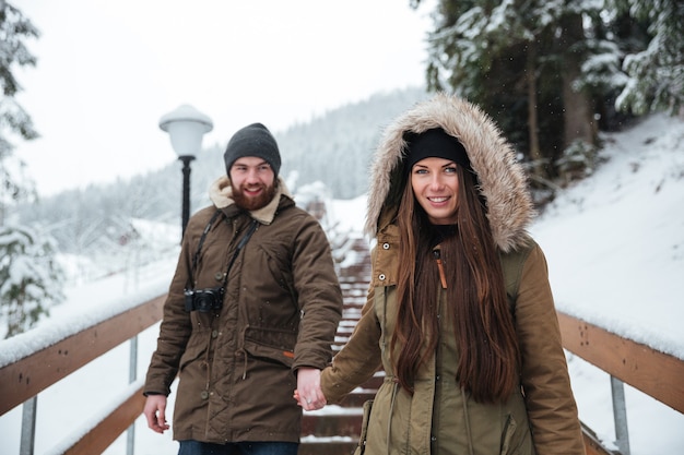 Glimlachend jong koppel hand in hand en lopen op trappen in de winter bergen