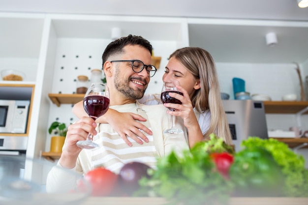 Glimlachend jong koppel koken samen eten in de keuken in de keuken hebben een geweldige tijd samen Man en vrouw lachen en wijn drinken