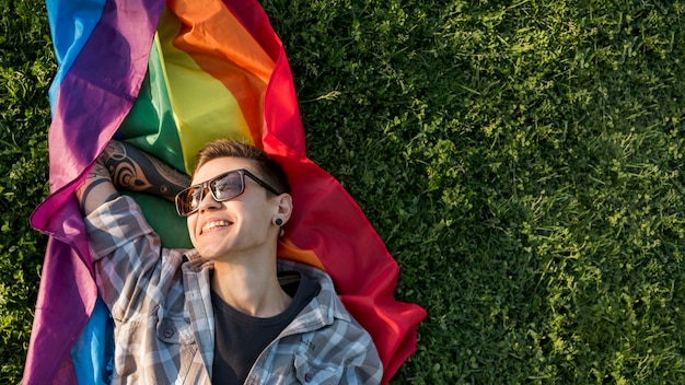 Glimlachend jong lesbisch rustend op regenboogvlag