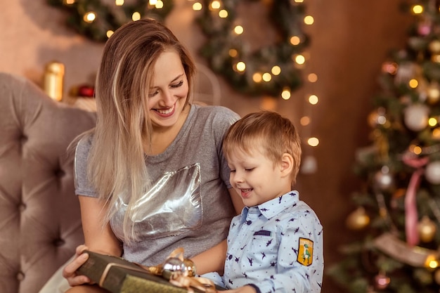 Glimlachend jong meisje en jongen zitten in een versierde kerstkamer en genieten van de feestdag en de geschenken