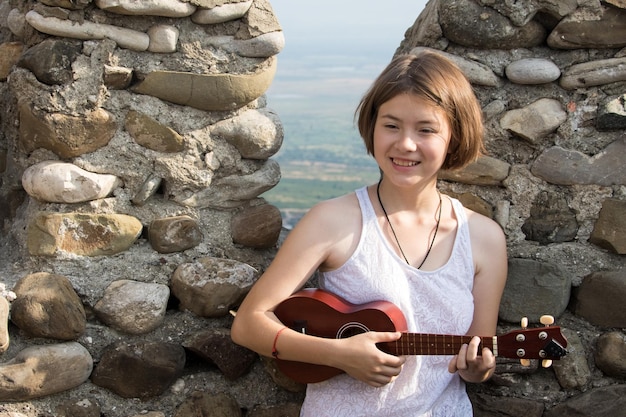 Glimlachend jong meisje met ukelele op dak van fort