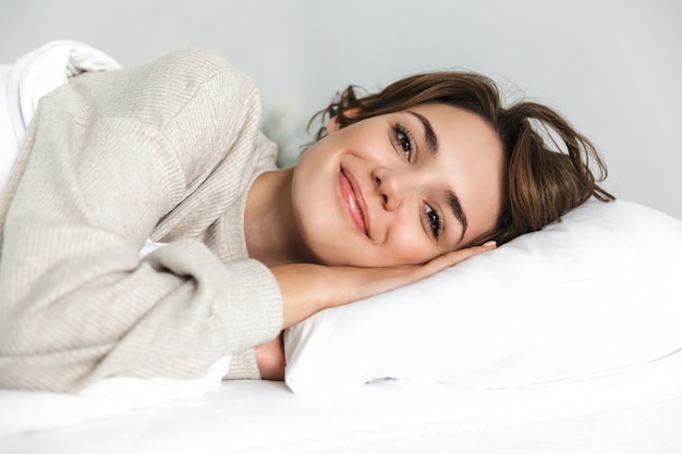 Glimlachend jong meisje ontspannen in bed in de ochtend