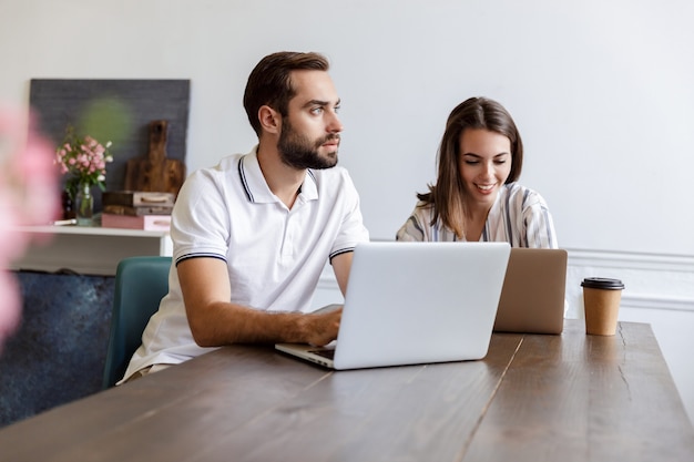 Glimlachend jong stel dat aan een project werkt terwijl ze thuis aan het bureau zitten