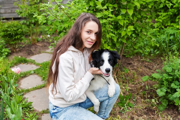 Glimlachend jonge aantrekkelijke vrouw omarmen knuffelen schattige puppy hondje border collie in zomer stadspark buiten achtergrond