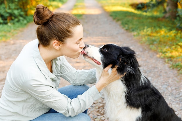 Glimlachend jonge aantrekkelijke vrouw spelen met schattige puppy hondje border collie op zomer buiten pagina