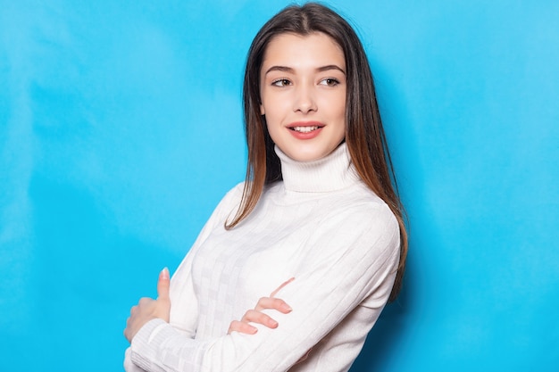 Glimlachend jonge brunette vrouw meisje in casual witte kleding, poseren geïsoleerd op pastel blauwe achtergrond studio portret. Mensen emoties levensstijl concept. Bespotten kopie ruimte. Camera kijken