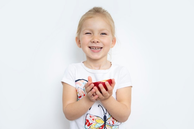 Glimlachend kind meisje blonde met een halve appel op een witte achtergrond