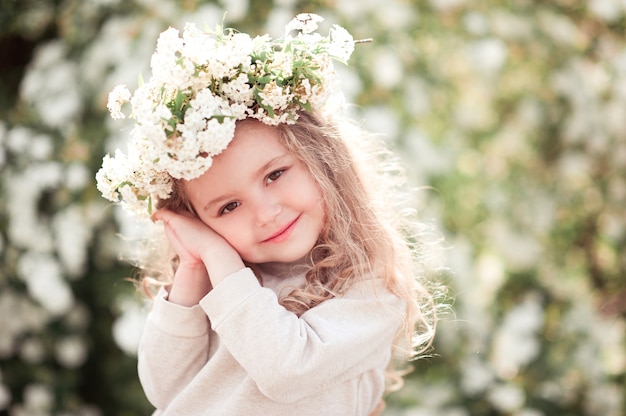 Glimlachend kind meisje poseren met bloemenkrans buitenshuis