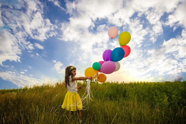 Glimlachend kind met plezier met ballonnen buiten tegen de blauwe hemelachtergrond. Vrijheidsconcept