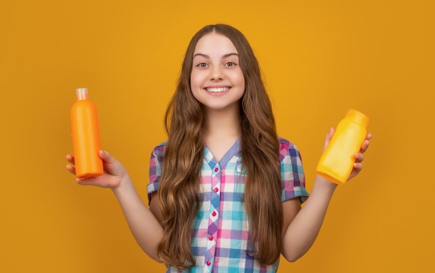 Glimlachend kind met shampoofles op gele achtergrond