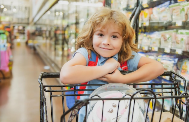 Glimlachend kind met winkelwagentje bij supermarkt of supermarkt