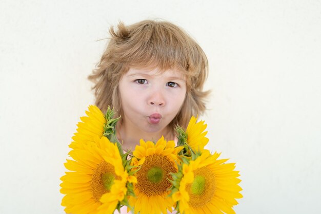 Glimlachend kind met zonnebloemen. Gelukkig kind met boeket bloemen. Leuke mooie jongen romantisch en verrassing.