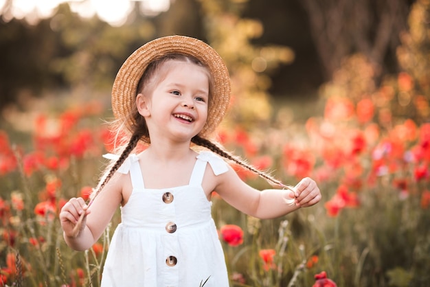Glimlachend kindmeisje met bloemstandaard in papaverweide buitenshuis