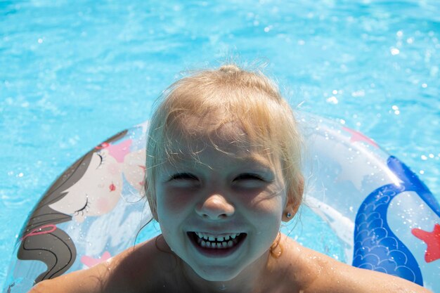 Glimlachend kindmeisje zwemt met een opblaasbare ring in het zwembad