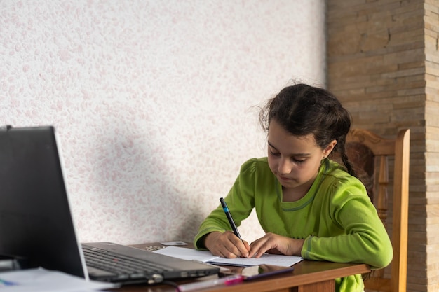 Glimlachend klein kaukasisch meisje met koptelefoon heeft een videogesprek in de verre klas met leraar die laptop gebruikt, gelukkig klein kind zwaaibegroeting met tutor, studeer online op computer, homeschooling concept.