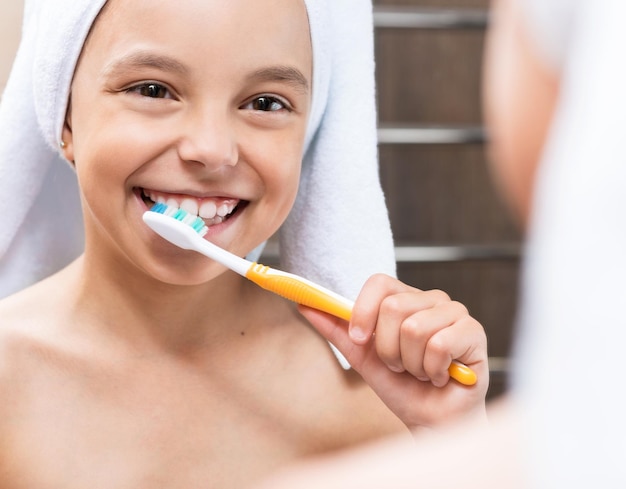 Glimlachend klein meisje dat haar tanden poetst in de badkamer Mooi gezond kind thuis tanden poetsten en zich klaarmaken voor bed Close-up opname