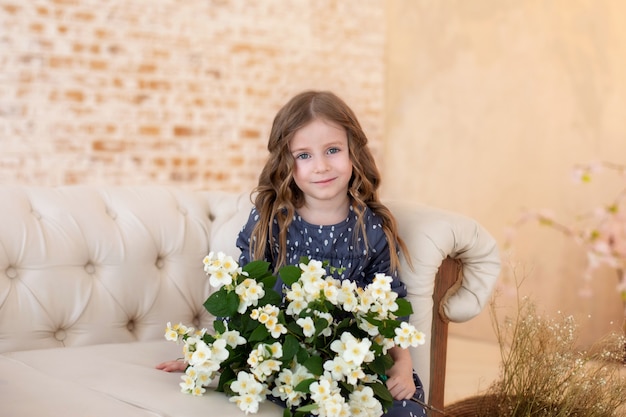 Glimlachend krullend meisje met boeket van jasmijnbloemen