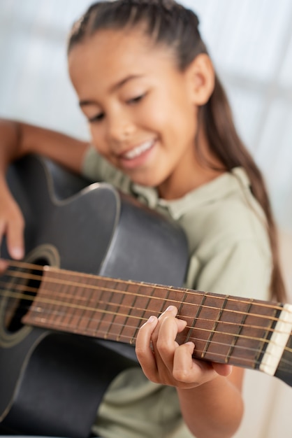 Glimlachend meisje dat gitaar leert spelen tijdens de les thuis