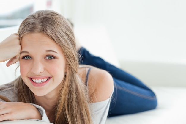 Glimlachend meisje die op de laag liggen aangezien zij de camera bekijkt